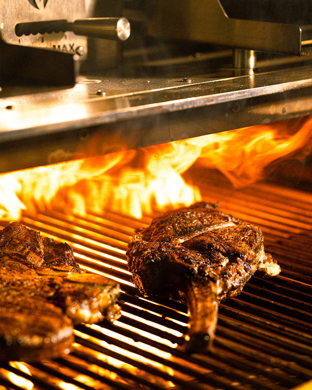 Steaks cooking over open flame