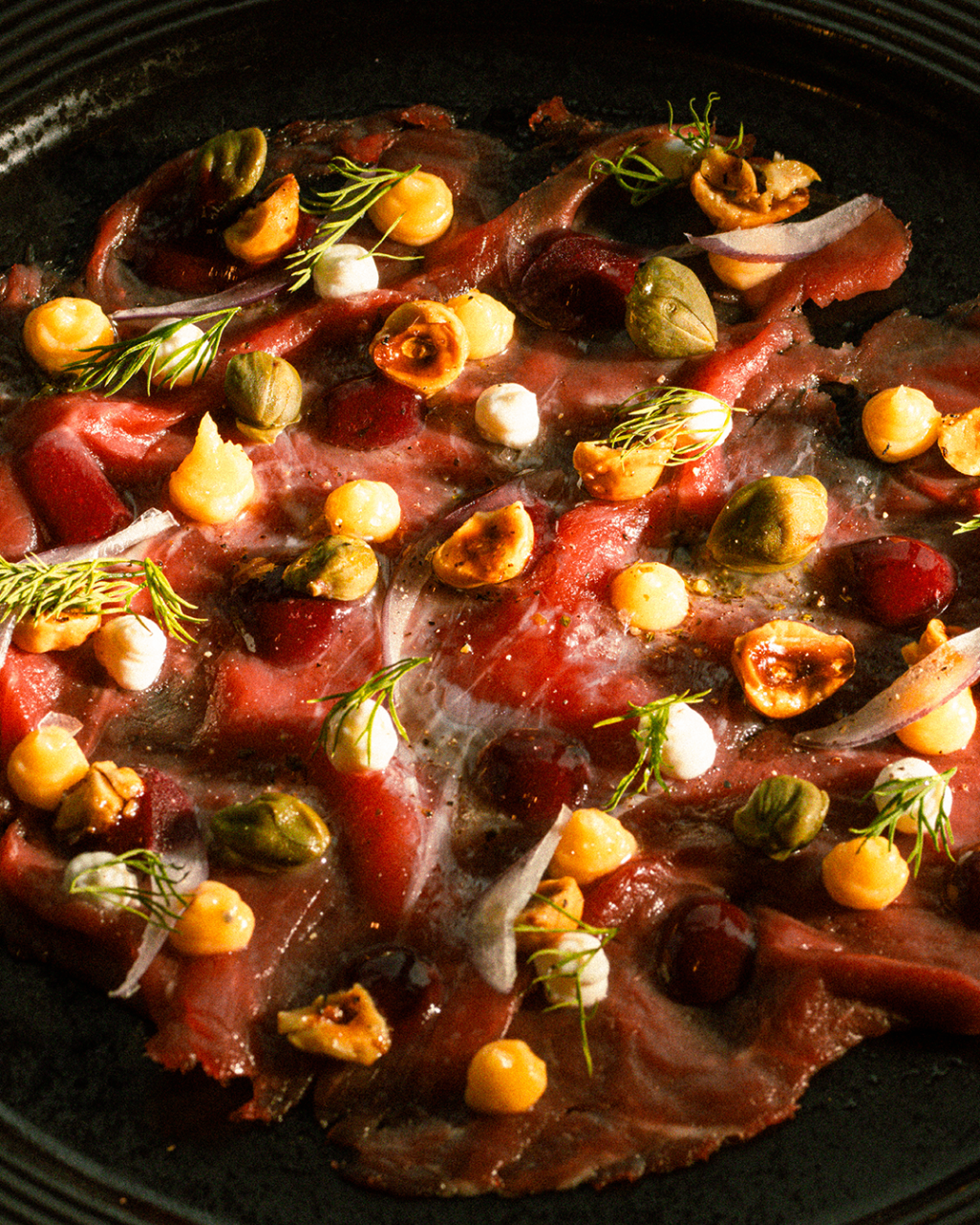 Beef carpaccio plated with herbs and garnish